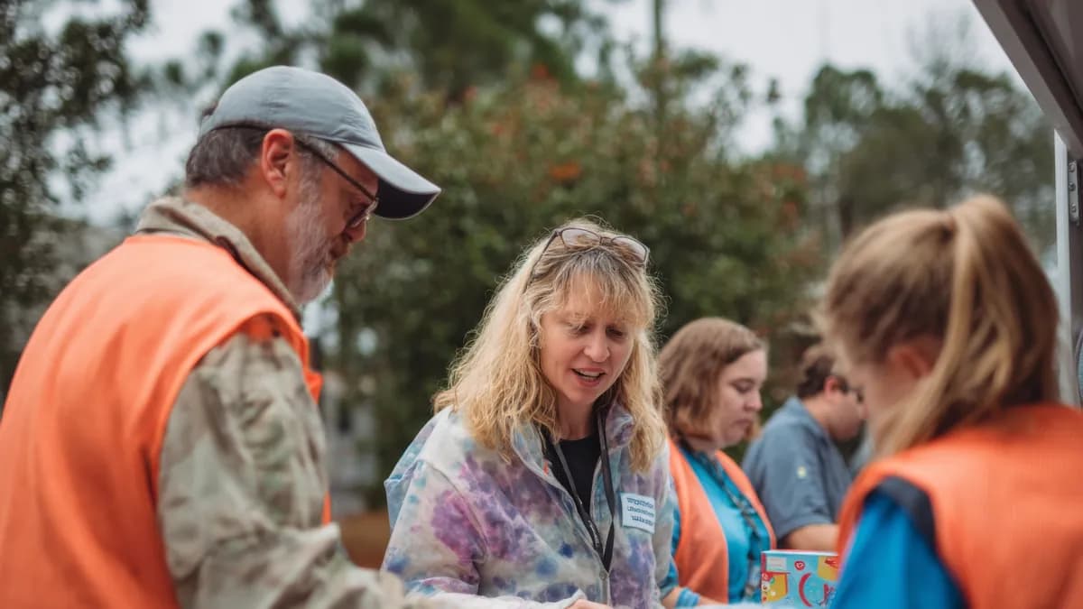 Man and woman in orange vests helping a veteran
