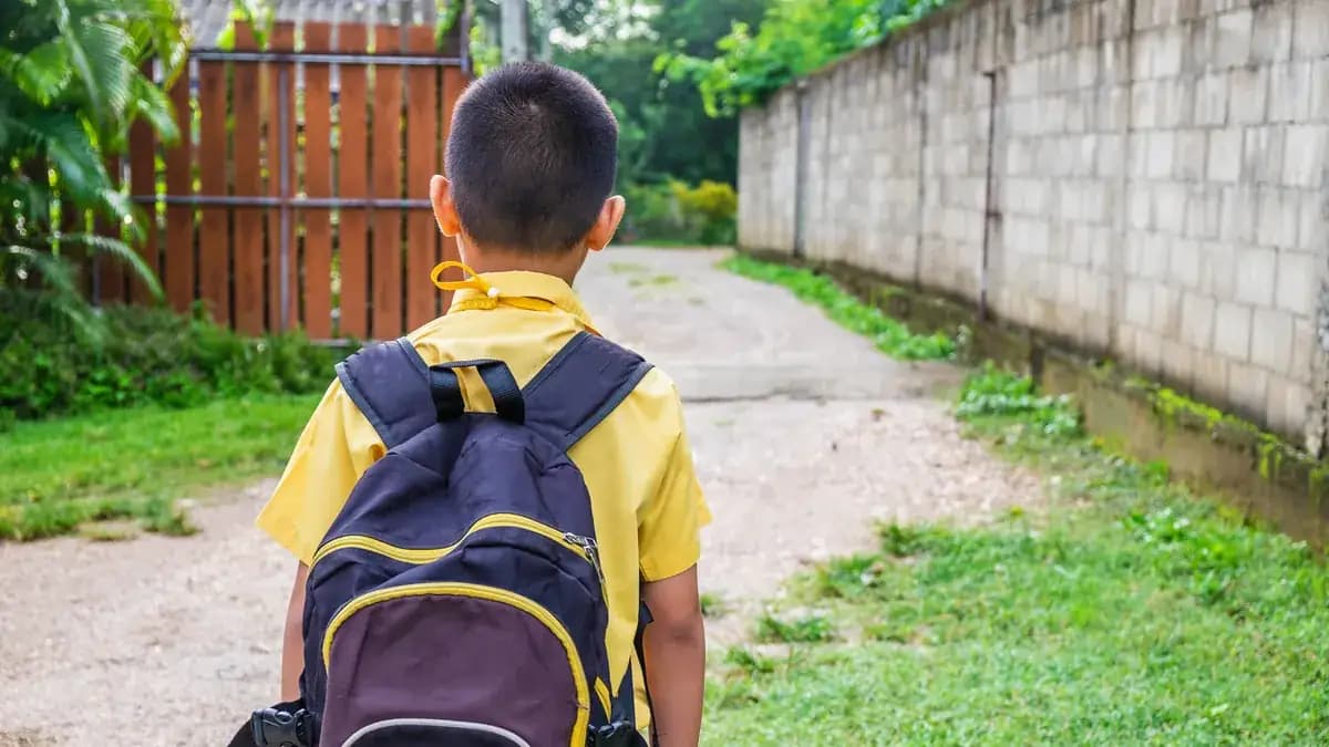 Boy in a yellow shirt with a backpack heading to school